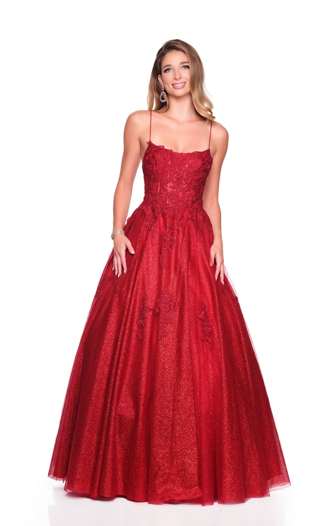 A woman models the Dave and Johnny 12727 long prom dress—a full-length red gown with thin straps, an embroidered bodice with floral embellishments, and a flared glitter tulle skirt—shown against a plain white background.